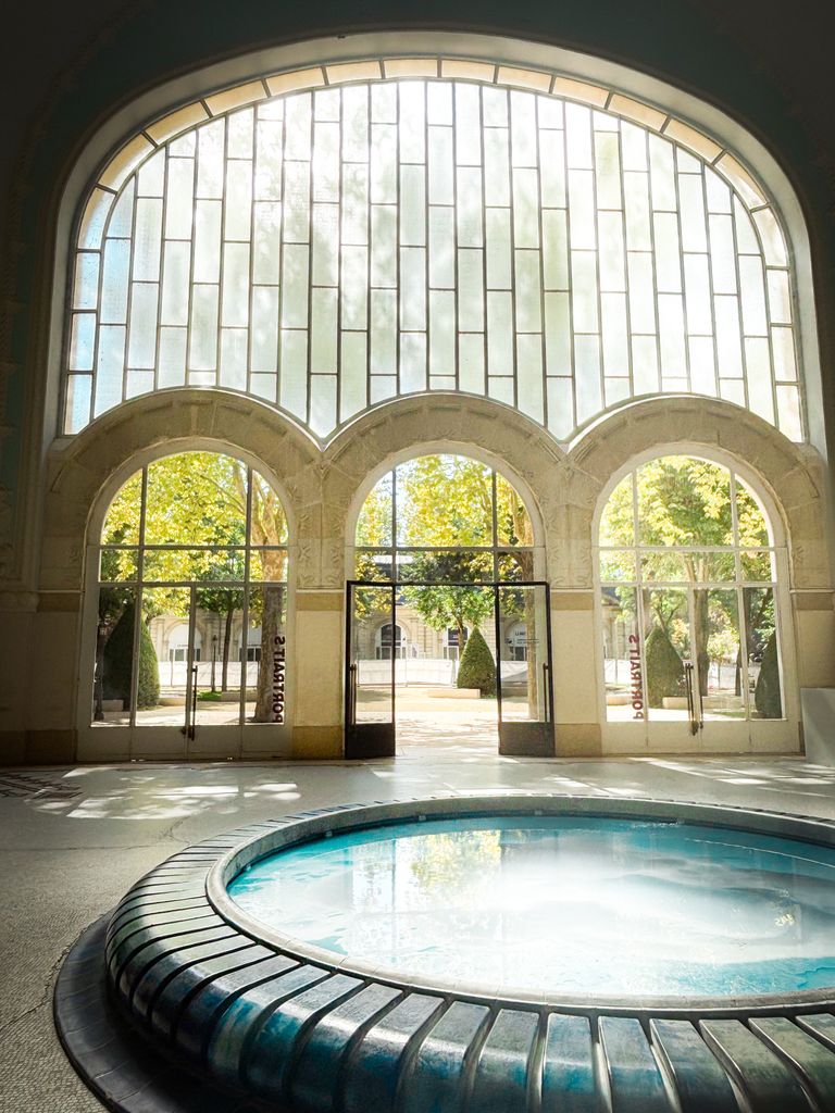 Elegant indoor pool area with large arched windows and sunlight streaming in.